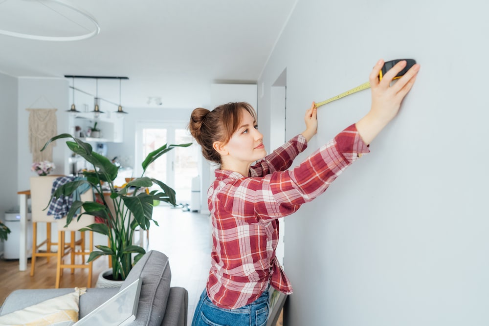 woman measuring wall with tape measure